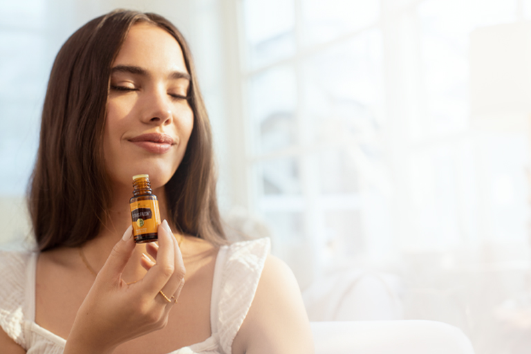 Image of woman gently inhaling essential oil from the bottle.