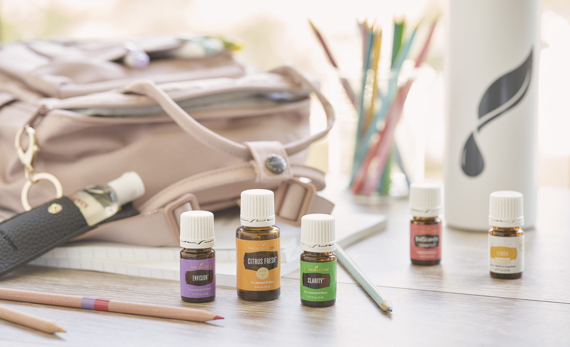 Envision, Citrus Fresh, Clarity, KidScents GeneYus, and Lemon Vitality essential oils surrounded by a backpack, YL Gear Drop bottle, Madison hand sanitizer holder, and other school supplies - Young Living Lavender Life Blog 